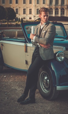 Confident wealthy young man with newspaper near classic convertibleの写真素材