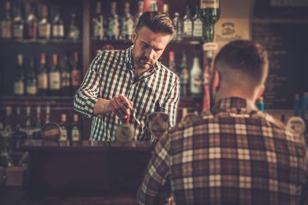 Handsome bartender pouring a pint of beer to customer in a pub.の写真素材