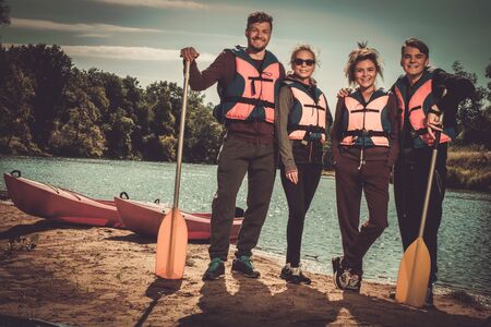 Cheerful friends having fun near kayaks on a beach.の写真素材