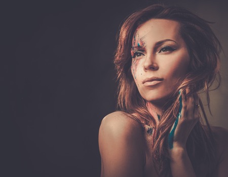 Portrait of beautiful woman with creative colored makeup on a dark background.の写真素材