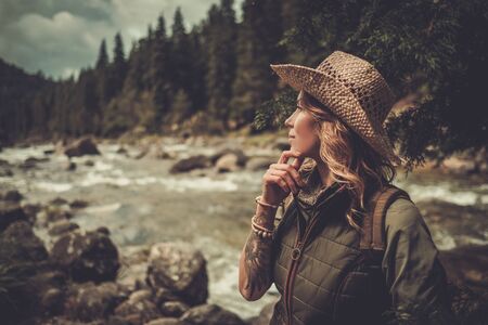 Beautiful woman hiker enjoying amazing landscapes near wild mountain river.の写真素材