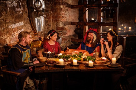 Medieval people eat and drink in ancient castle kitchen interior.の写真素材