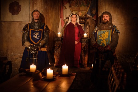 Medieval queen with her knights on guard in ancient castle interior.の写真素材