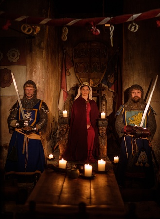 Medieval queen with her knights on guard in ancient castle interior.の写真素材