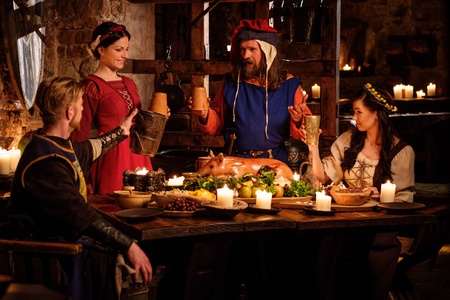 Medieval people eat and drink in ancient castle kitchen interior.の写真素材