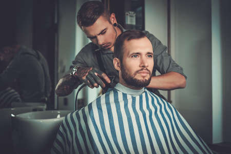 Confident man visiting hairstylist in barber shop.