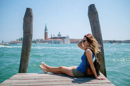 Woman traveler sitting on the wooden pier with Saint George island on the background.の写真素材