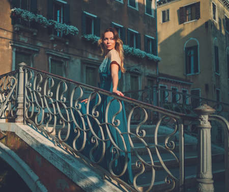 Beautiful well-dressed woman posing on a bridge over the canal in Venice.の写真素材