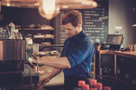 Handsome barista preparing cup of coffee for customer in coffee shop.