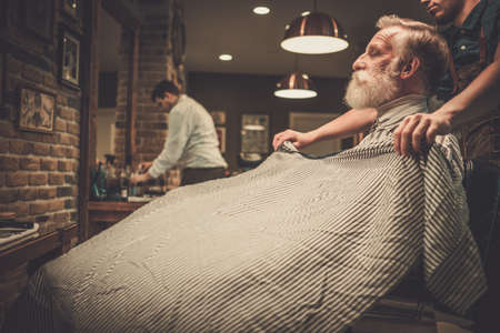 Senior man visiting hairstylist in barber shop.の写真素材