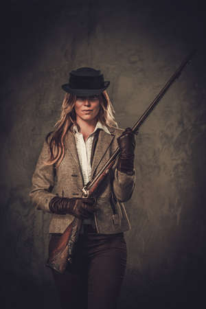 Lady with shotgun from wild west on dark background.