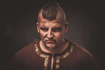 Angry viking in a traditional warrior clothes on a dark background.の写真素材