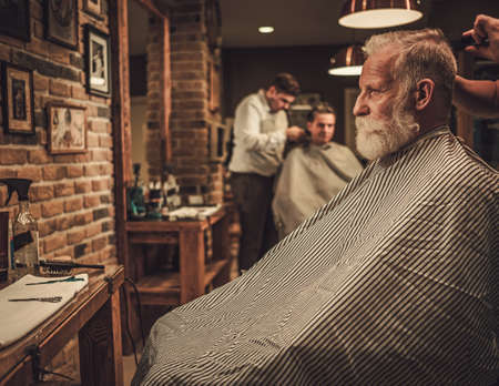 Senior man visiting hairstylist in barber shop.の写真素材