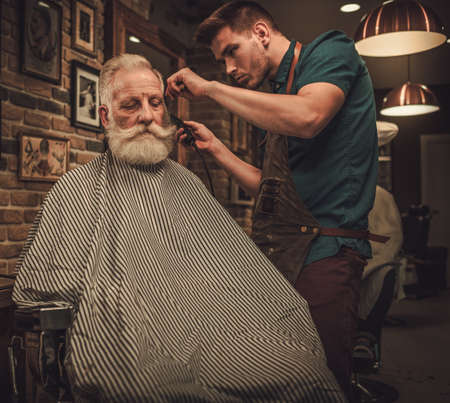 Senior man visiting hairstylist in barber shop.の写真素材