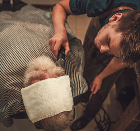 Senior man visiting hairstylist in barber shop.の写真素材