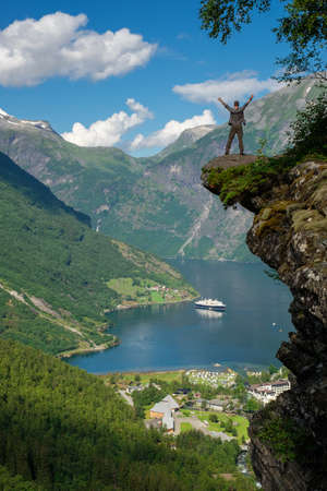 Man hiker enjoying scenic landscapes at a cliff edge, Geirangerfjord, Norwayの写真素材