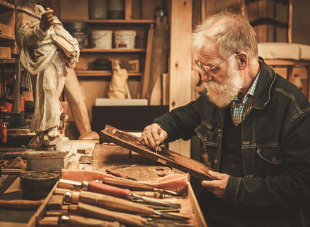 Senior restorer working with antique decor element in his workshop.の写真素材