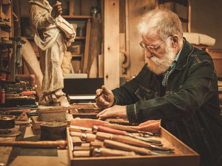 Senior restorer working with antique decor element in his workshop.の写真素材