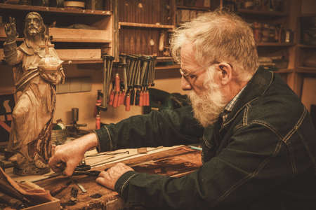 Senior restorer working with antique decor element in his workshop.の写真素材