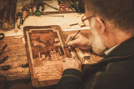 Senior restorer working with antique decor element in his workshop.の写真素材