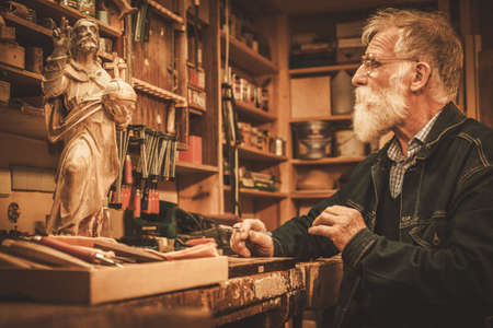 Senior restorer working with antique decor element in his workshop.の写真素材