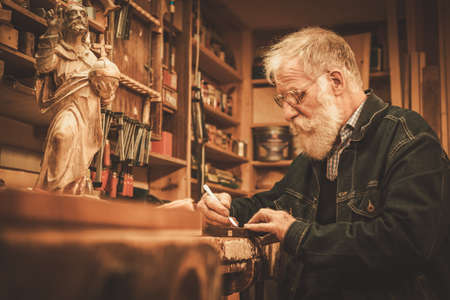 Senior restorer working with antique decor element in his workshop.の写真素材