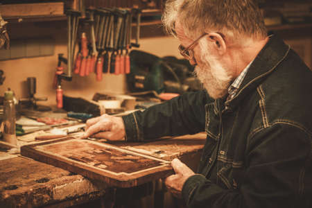 Senior restorer working with antique decor element in his workshop.の写真素材