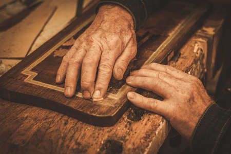 Close-up of restorer hands working with antique decor element in his workshop.の写真素材