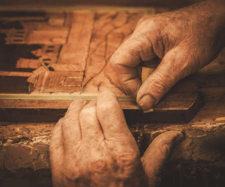 Close-up of restorer hands working with antique decor element in his workshop.の写真素材