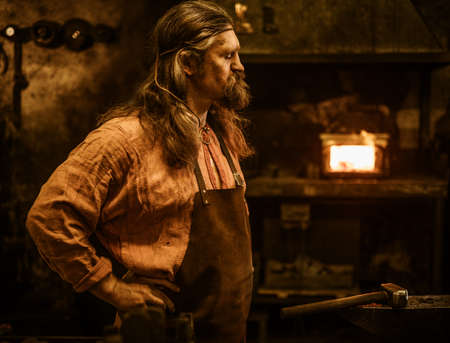 Senior blacksmith standing in smithy.の写真素材