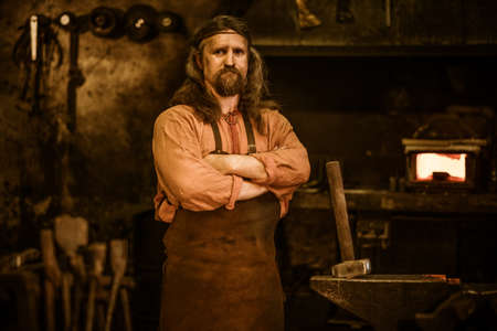 Senior blacksmith standing in smithy.