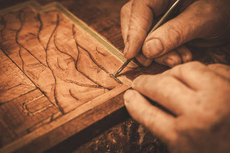 Close-up of restorer hands working with antique decor element in his workshop.の写真素材