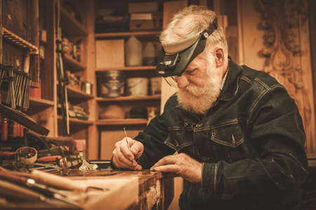 Senior restorer working with antique decor element in his workshop.の写真素材