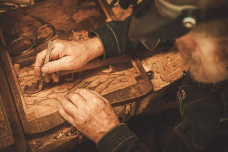 Senior restorer working with antique decor element in his workshop.の写真素材