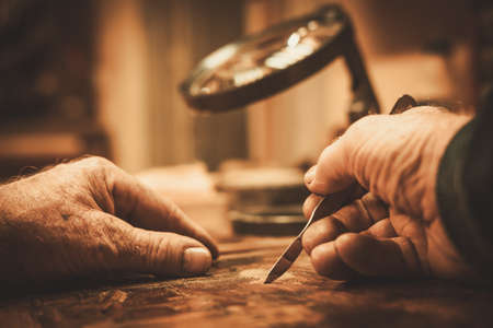 Senior restorer working with antique decor element in his workshop.