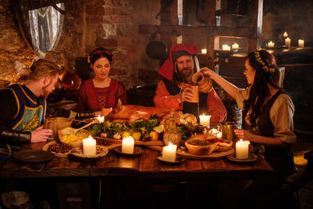 Medieval people eat and drink in ancient castle kitchen interior.の写真素材