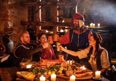 Medieval people eat and drink in ancient castle kitchen interior.の写真素材