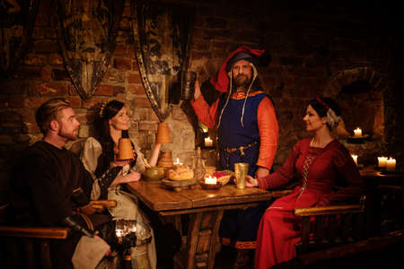 Medieval people eat and drink in ancient castle tavern.の写真素材