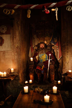 Old medieval king on the throne in ancient castle interior.の写真素材