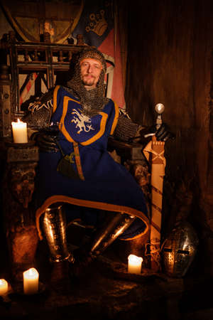 Old medieval king on the throne in ancient castle interior.の写真素材