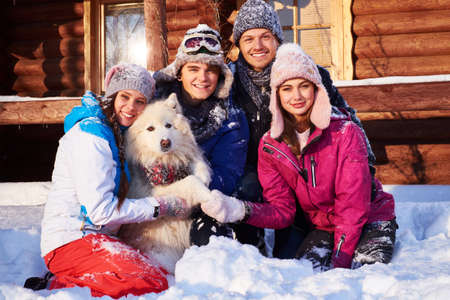 Cheerful friends with dog spend winter holidays together at mountain cottageの写真素材