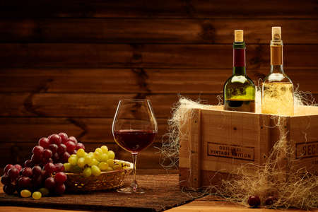 Bottles of red and white wine on a wooden interior.の写真素材