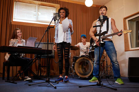 Multiracial music band performing in a recording studio.