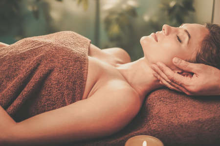 Young woman having face massage in a spa salon.の写真素材