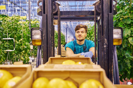 Young attractive man working on electric forklift in greenhouse.の写真素材