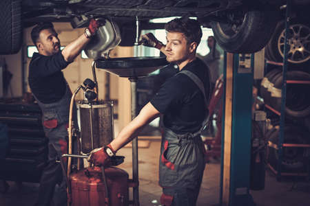Profecional car  mechanic changing motor oil in automobile engine at maintenance repair service station in a car workshop.の写真素材