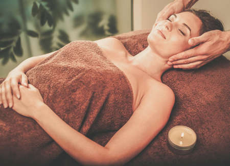 Young woman having face massage in a spa salon.の写真素材