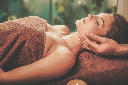 Young woman having face massage in a spa salon.の写真素材