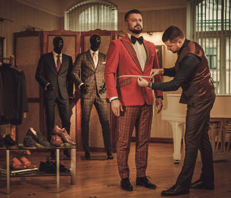 Tailor measuring client for custom made suit tailoring.