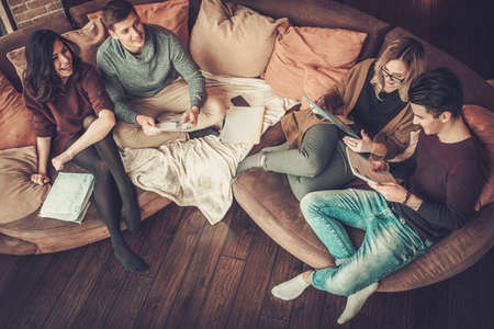 Group of multi ethnic young students preparing for exams in home interior.